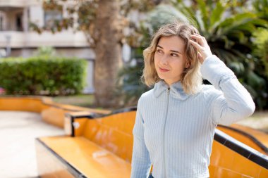 Güzel kadın şaşkın ve kafası karışmış hissediyor, başını kaşıyor ve yan tarafa bakıyor.