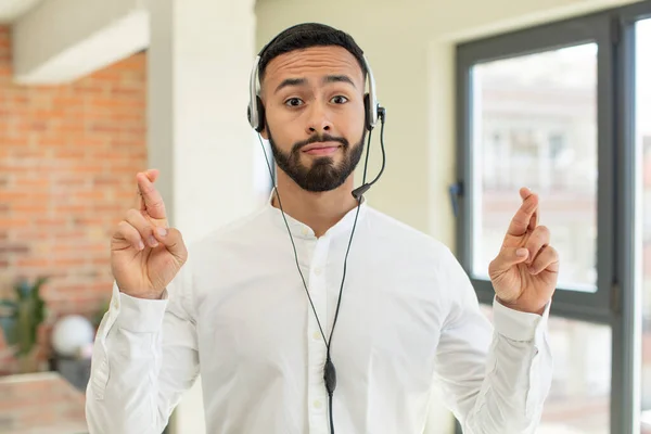 stock image young  adult man crossing fingers and hoping for good luck. telemarketer concept