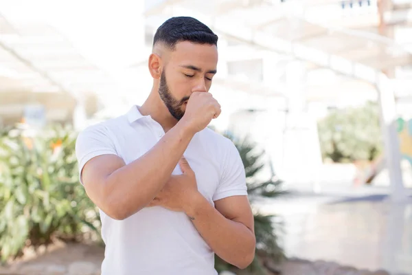 喉の痛みやインフルエンザの症状で苦しんでいる若いハンサムな男は口で咳をして — ストック写真