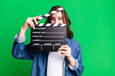 Genç ve güzel bir kadın, elinde alkışlı bir sinema tahtası tutuyor.