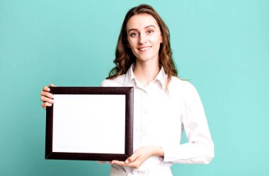 Genç ve güzel bir kadın boş bir çerçeve kopyası tutuyor.