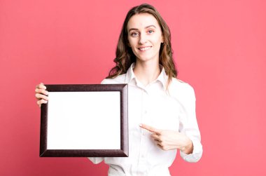 Genç ve güzel bir kadın boş bir çerçeve kopyası tutuyor.