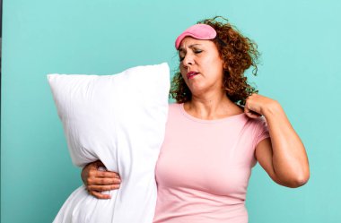 Güzel, orta yaşlı bir kadın stresli, endişeli, yorgun ve sinirli gece pijaması ve yastık giyiyor.