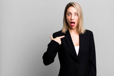 Şok olmuş ve ağzı açık, kendini işaret eden güzel sarışın bir kadın. İş kadını kavramı