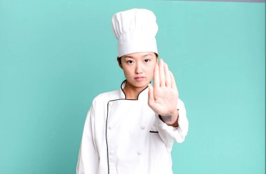 Güzel Asyalı kadın ciddi görünüyor. Avuç içini gösteriyor. Durdurma hareketi yapıyor. restoran şefi konsepti