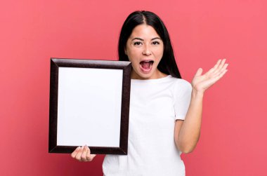 İspanyol güzel kadın kendini mutlu hissediyor ve boş bir çerçeveyle inanılmaz bir şeye hayret ediyor.