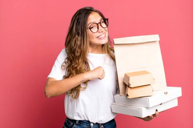 İspanyol güzel kadın kendini mutlu hissediyor ve bir meydan okumayla yüzleşiyor ya da kutluyor. Fast food paketleriyle