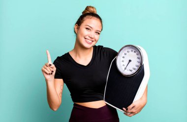 İspanyol güzel kadın gülümsüyor ve arkadaş canlısı görünüyor, bir numarayı gösteriyor. fitness ve diyet konsepti