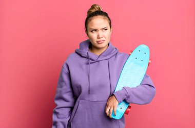 hispanic pretty woman feeling sad, upset or angry and looking to the side. skate boarding concept
