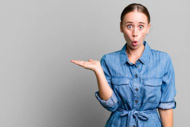 Kafkas güzel kadın şaşırmış ve şok olmuş görünüyor, çenesi düşmüş bir nesne tutuyor.