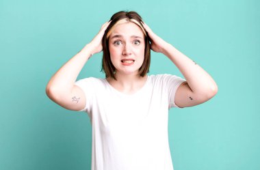 Genç ve güzel bir kadın stresli, endişeli ya da korkmuş hissediyor, elleri başının üstünde.