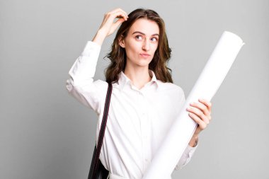 young pretty woman smiling happily and daydreaming or doubting. architect concept