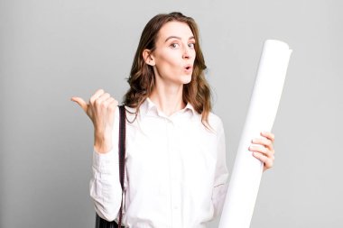 young pretty woman looking astonished in disbelief. architect concept