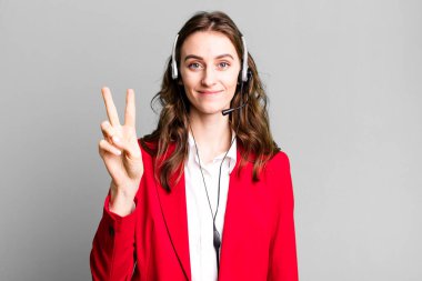 Genç, güzel bir bayan gülümsüyor ve iki numarayı gösteriyor. tele pazarlamacı kavramı