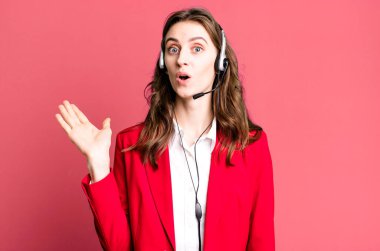 Genç ve güzel bir kadın şaşırmış ve şok olmuş görünüyor. Çenesi düşmüş ve elinde bir nesne tutuyor. tele pazarlamacı kavramı