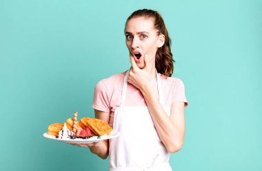 Ağzı ve gözleri açık, eli çenesinde genç ve güzel bir kadın. Waffle konsepti