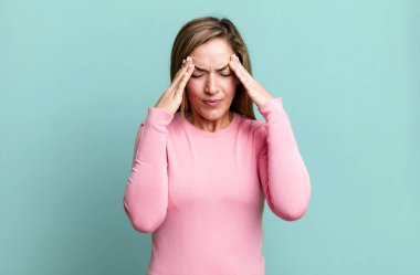 blonde adult woman looking stressed and frustrated, working under pressure with a headache and troubled with problems