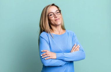 blonde adult woman laughing happily with arms crossed, with a relaxed, positive and satisfied pose