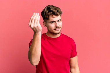 young adult caucasian man making capice or money gesture, telling you to pay your debts!