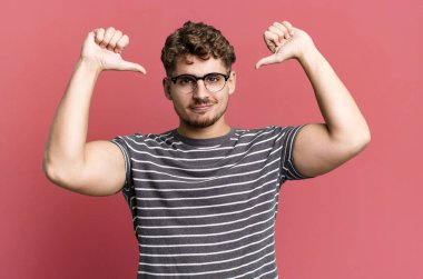 young adult caucasian man feeling proud, arrogant and confident, looking satisfied and successful, pointing to self