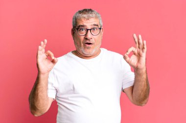 Orta yaşlı bir adam şok olmuş, şaşırmış ve şaşırmış hissediyor. Onaylıyor. İki eliyle de onay imzası atıyor.