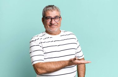 Orta yaşlı, neşeli bir şekilde gülümseyen, mutlu hisseden ve fotokopi alanında avucunun içinde bir konsept gösteren son sınıf öğrencisi.