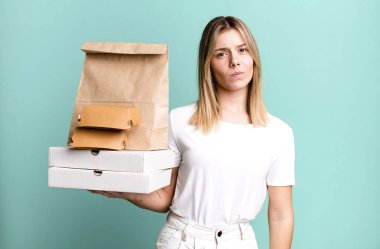 Genç, güzel bir kadın üzgün, üzgün ya da kızgın hissediyor ve yan tarafa bakıyor. Yemek teslimatı ve paket servis.