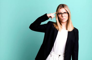 Genç ve güzel bir kadın kafası karışık ve şaşkın hissediyor, deli olduğunu gösteriyor. iş kavramı