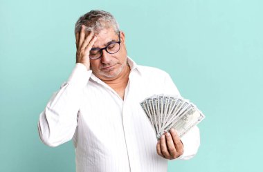 Orta yaşlı bir adam bıkkın, yorgun ve uykulu hissediyor. Dolar banknotları konsepti