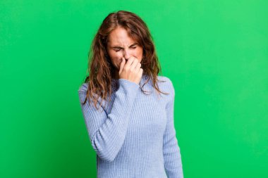 Genç ve güzel bir kadın iğrenç ve nahoş bir kokuyu koklamamak için burnunu tutuyor.