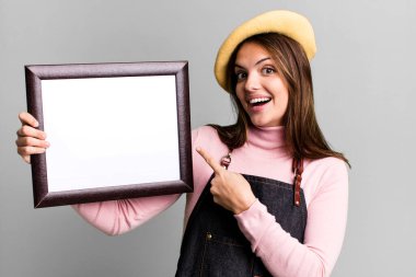 young pretty woman with an empty picture frame copy space
