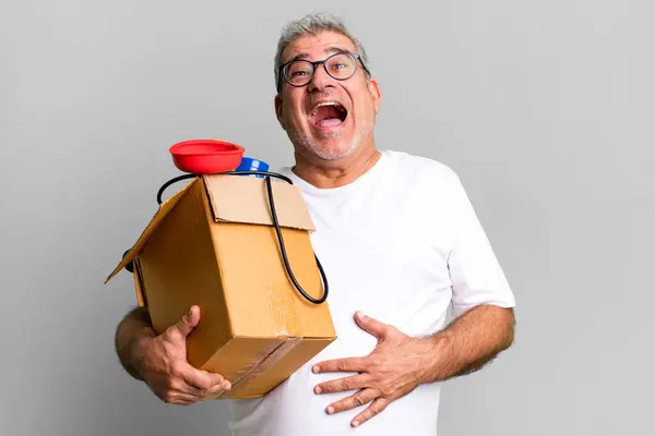 middle age senior man laughing out loud at some hilarious joke. housekeeper repairman with a toolbox concept