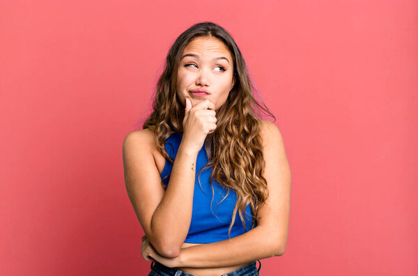 young pretty woman thinking, feeling doubtful and confused, with different options, wondering which decision to make