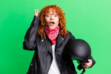 Kızıl saçlı güzel kadın ellerini havaya kaldırarak çığlık atıyor. Motosiklet sürücüsü konsepti