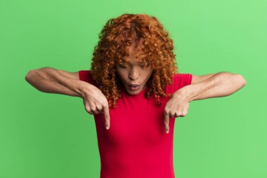 Kızıl saçlı, güzel bir kadın şok olmuş, ağzı açık ve şaşkın, inançsızlık ve şaşkınlık içinde bakıyor ve onu işaret ediyor.