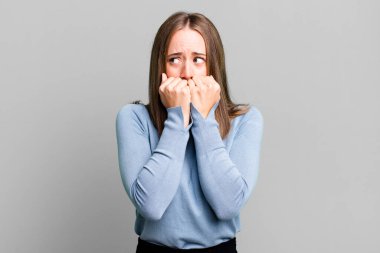 Endişeli, endişeli, stresli ve korkmuş görünüyor, tırnaklarını yiyor ve yanal kopya alanı arıyor.