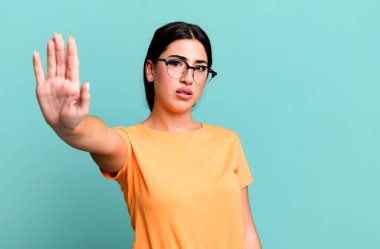 Ciddi, sert, hoşnutsuz ve kızgın görünüyor. Avuç içini açıp, jestleri durduruyor.