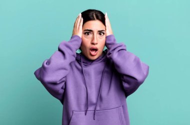 Kötü bir şekilde şoke olmuş, korkmuş ya da endişeli, ağzı sonuna kadar açık ve iki kulağını da eliyle kapatmış.