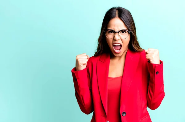 hispanic pretty woman shouting aggressively with an angry expression. businesswoman concept