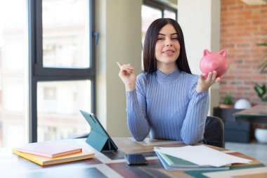 Güzel, genç bir bayan neşeyle gülümsüyor, mutlu hissediyor ve bir tarafı işaret ediyor. Domuz kumbarası konsepti