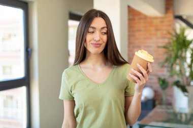 Gülümsüyor ve mutlu ve kendinden emin bir ifadeyle bakıyor. kahve konseptini kaldır.