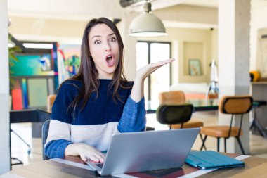 Genç ve güzel bir kadın şaşırmış ve şok olmuş görünüyor. Çenesi düşmüş ve elinde bir nesne tutuyor. Evden işe dolaşma kavramı