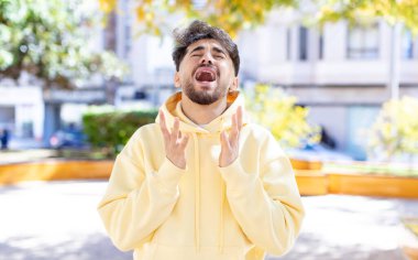 Genç yakışıklı adam umutsuz ve sinirli görünüyor, stresli, mutsuz ve sinirli, bağırıyor ve çığlık atıyor.