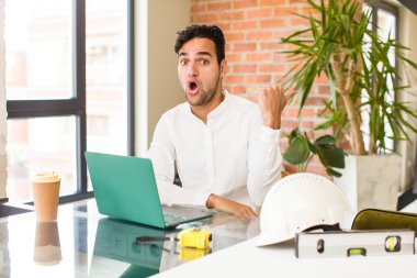 Genç İspanyol adam inançsızlıktan şaşkın şaşkın bakıyor, yan taraftaki objeyi işaret edip 