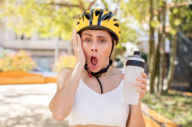 Genç ve güzel bir kadın şok olmuş ve şaşırmış hissediyor. bisiklet kaskı konsepti
