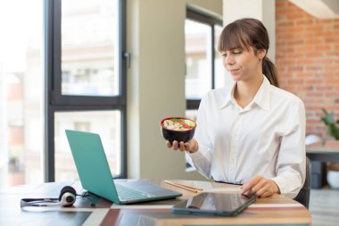 Genç ve güzel bir kadın gülümsüyor ve kendine güveni tam bir ifadeyle bakıyor. ramen kasesi konsepti