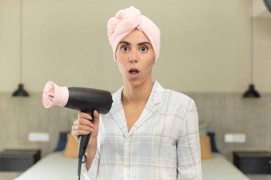 Genç ve güzel bir kadın şok olmuş ve şaşırmış hissediyor. saç kurutma makinesi konsepti