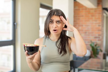 Genç kadın mutlu, şaşkın ve şaşırmış görünüyor. ramen kasesi