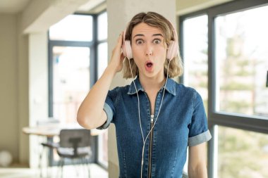Güzel bir kadın son derece şaşırmış ve şok olmuş hissediyor. kulaklıklar ve müzik konsepti