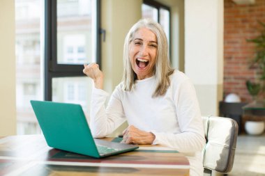 Yaşlı, güzel bir kadın kızgın, sinirli ve dizüstü bilgisayarla hayal kırıklığına uğramış görünüyor.